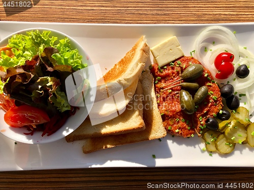 Image of Steak tartare served with side dishes, toast and salad