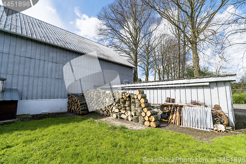 Image of Barnyard with green grass and a woodstack