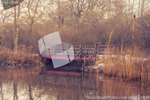 Image of Small bridge with red paint by a river