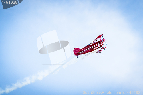 Image of Red airplane with propellers and white smoke