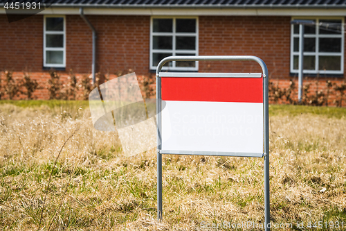 Image of Real estate sign on a lawn in front of a house