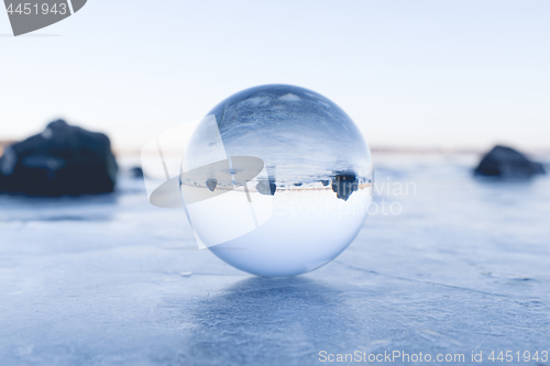 Image of Glass orb balancing on ice on a frozen lake