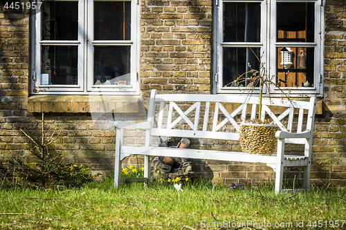 Image of White bench outside an old brick house