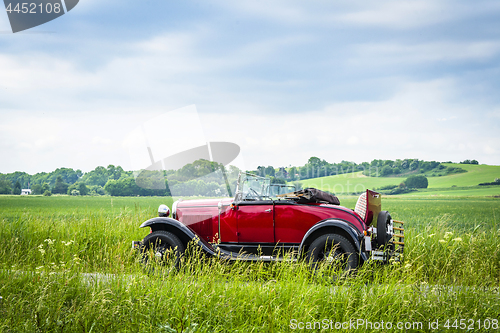 Image of Red veteran car on a countryside road