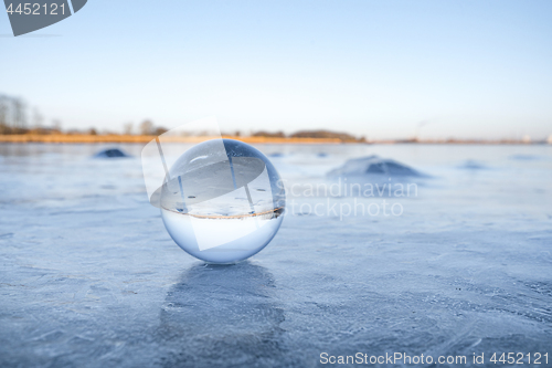 Image of Transparent glass orb on a frozen lake with ice