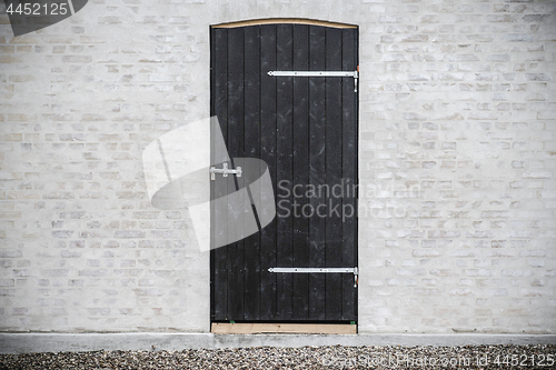 Image of Black wooden door on a grey brick wall