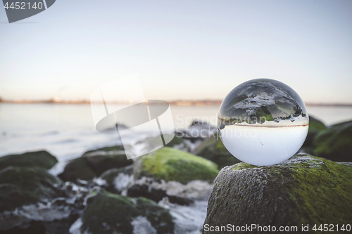 Image of Glass orb on rocks by the sea