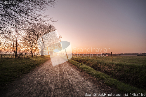 Image of Countryside trail in the morning sunrise with rural fields