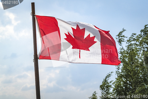 Image of Canada flag on a flagstaff with the flag waving
