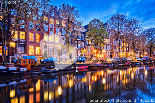Image of Amterdam canal, boats and medieval houses in the evening