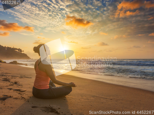 Image of Woman doing yoga oudoors at beach - Padmasana lotus pose