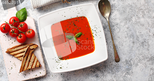 Image of Red tomato soup with crisp bread and spoon