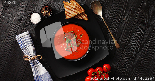 Image of Tomato soup in black bowl with crisp bread 