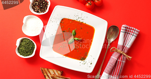 Image of Tomato soup served in plate with spoon