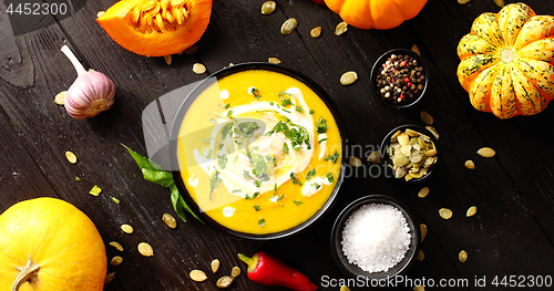 Image of Yellow fresh pumpkin soup surrounded by spices and seeds