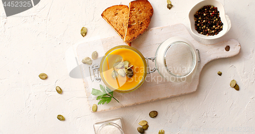 Image of Pumpkin soup in glass jar on cutting board