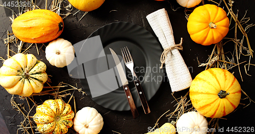 Image of Black plate surrounded by yellow pumpkins