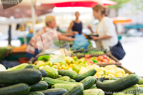 Image of Blured unrecodnised people buying homegrown vegetable at farmers\' market stall with variety of organic vegetable.