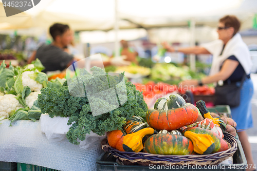 Image of Blured unrecodnised people buying homegrown vegetable at farmers\' market stall with variety of organic vegetable.