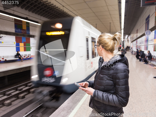 Image of Woman with a cell phone waiting for metro.