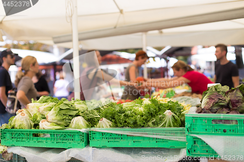 Image of Blured unrecodnised people buying homegrown vegetable at farmers\' market stall with variety of organic vegetable.