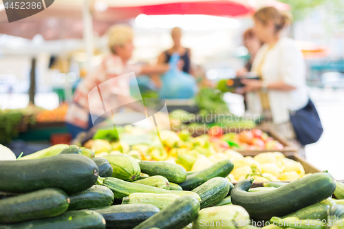 Image of Blured unrecodnised people buying homegrown vegetable at farmers\' market stall with variety of organic vegetable.