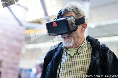 Image of Senior man wearing virtual reality goggles watching virtual reality presentation.