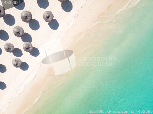 Image of Aerial view of amazing tropical white sandy beach with palm leaves umbrellas and turquoise sea.