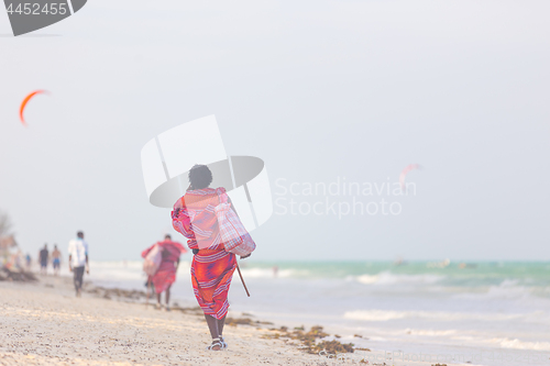 Image of Rear view of traditonaly dressed maasai man selling hand made jewelry on picture perfect tropical Paje beach, Zanzibar, Tanzania, East Africa.