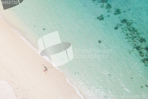 Image of Aerial shot of woman enjoying the picture perfect white tropica beach on Mauritius island.