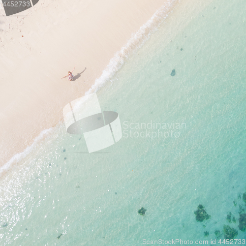 Image of Aerial shot of woman enjoying the picture perfect white tropica beach on Mauritius island.
