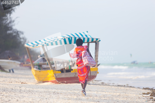 Image of Rear view of traditonaly dressed maasai man selling hand made jewelry on picture perfect tropical Paje beach, Zanzibar, Tanzania, East Africa.