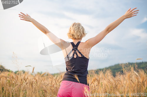 Image of Relaxed sporty woman, arms rised, enjoying nature in the beautifull morning at wheet field.