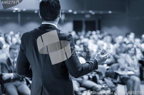 Image of Public speaker giving talk at business event.