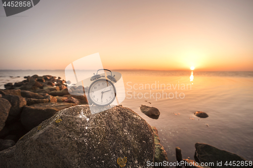 Image of Alarm clock in the sunrise by the sea