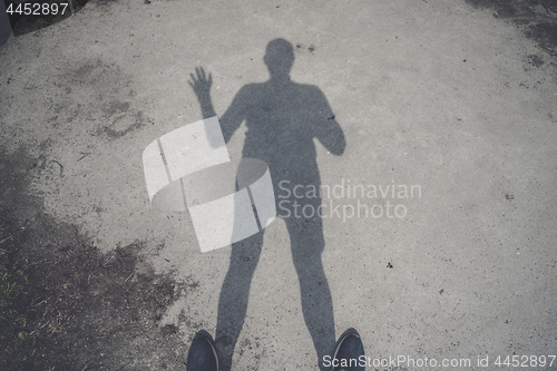 Image of Male shadow on the ground waving