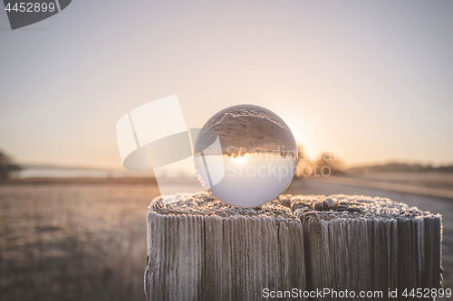 Image of Glass orb on a wooden post in the sunrise