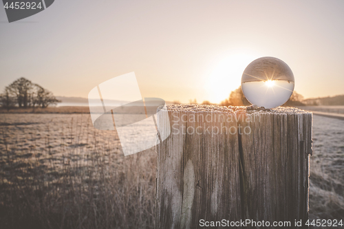 Image of Winter sunrise with sun in a glass orb