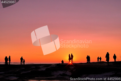 Image of Dark silhouettes of people on winter sunset background