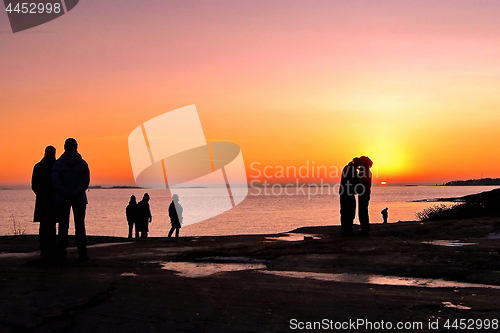 Image of Dark silhouettes of people on winter sunset background