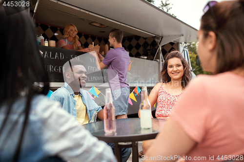 Image of friends with drinks sitting at table at food truck