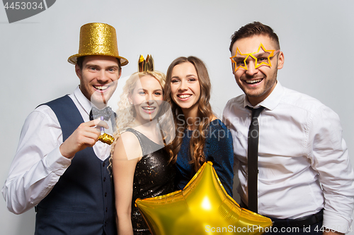 Image of happy friends with golden party props posing