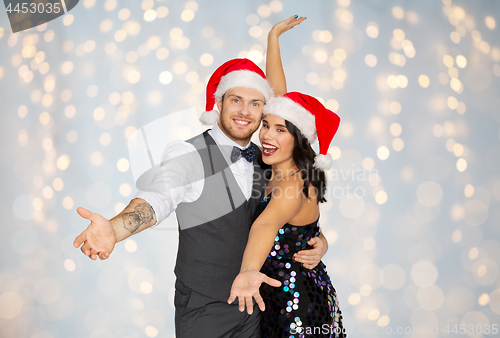 Image of happy couple in santa hats at christmas party