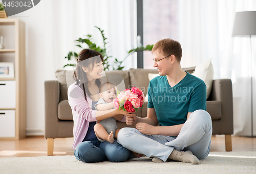 Image of happy family with flowers and baby boy at home