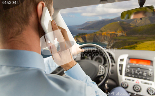 Image of businessman calling on smartphone and driving car