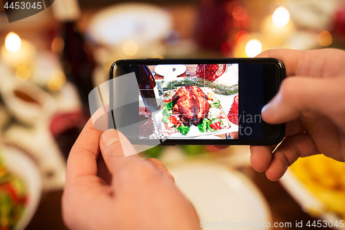 Image of hands photographing food at christmas dinner