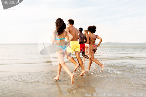 Image of happy friends running on summer beach