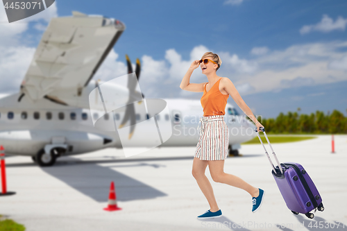 Image of happy teenage girl with travel bag over plane