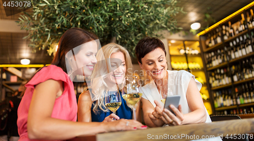 Image of women with smartphone at wine bar or restaurant