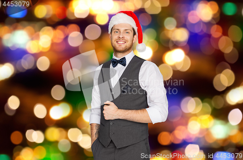 Image of happy man in santa hat and suit on christmas